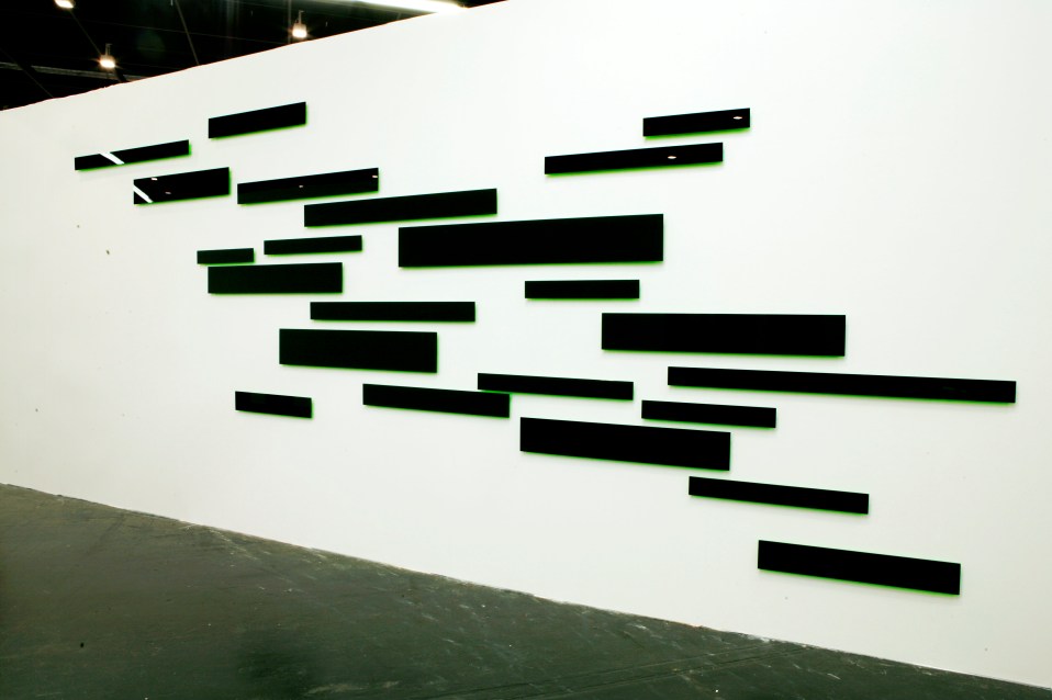 Die skulpturale Wandarbeit ‚Persistence Of Loss‘ (2009, ca. 350 x 750 cm) besteht aus von hinten schwarz lackierten Glasplattenstreifen in verschiedenen Formaten, die in unregelmäßigen Abständen unterschiedliche Partien der Wände bedecken. Die Segmente sind nicht unmittelbar auf der Wand befestigt, sondern schweben etwa zwei Zentimeter davor.  Durch die fluoreszierend grüne Lackierung ihrer Rückseite löst sich die Mauer hinter ihnen zu einer farbig leuchtenden zweiten Ebene auf, die den Raum entgrenzt und vor der die einzelnen Elemente der Verkleidung zu schweben scheinen. Das Modulare der einzelnen Bestandteile der Plastik weckt nicht nur die Vision von einer stets möglichen räumlichen Erweiterung, sondern transportiert auch eine zeitliche Komponente von Veränderung und Dynamik. Die Reflexionen der ‚gelackten‘ Glasoberflächen zitieren das spezifische ästhetische Vokabular einer urbanen Nachtsituation, die Verschiebung der Dimensionen, die der Passant beim Durchlaufen oder -fahren der nächtlichen Stadt erlebt: die Wandarbeit öffnet sich der Umgebung, nimmt sie auf, gibt sie wieder, verschluckt und verschiebt sie.